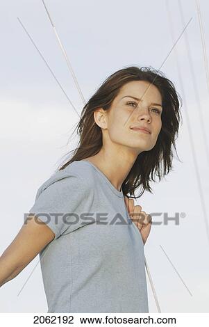Stock Image - Young Woman Wearing Hemp Shirt Holds Rope On Sailboat, Clear Lake, Riding Mountain National Park, Manitoba, Canada. Fotosearch
