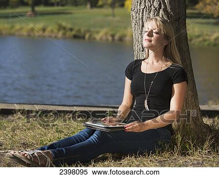Young woman with a tablet in a park; Edmonton, Alberta, Canada View Large Photo Image Stock Photography - Young woman with a tablet in a park; Edmonton, Alberta, Canada. Fotosearch