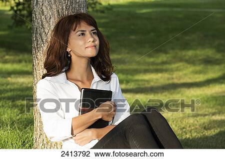 Stock Image - Young woman with her Bible in a park; Edmonton, Alberta, Canada. Fotosearch