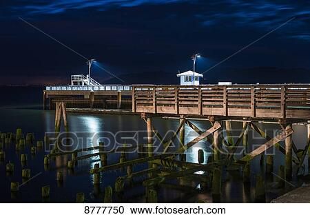 Stock Image - 17th Street Pier is illuminated on a summer evening; Astoria, Oregon, United States of America. Fotosearch
