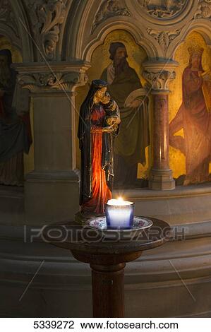 Stock Image - A candle burning on a small round table in a church; Northumberland, England. Fotosearch