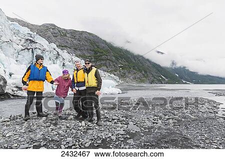 Stock Photo - A family poses in front of Shoup glacier and Chugach mountains, Shoup Bay State Marine Park, Prince William Sound; Valdez, Alaska, United States of America. Fotosearch