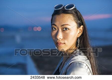 Stock Photo - A female model posing on a roof at sunset; Xiamen, China. Fotosearch