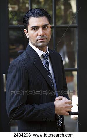 Stock Image - A man in a dark suit standing by a door; San Francisco, California, United States of America. Fotosearch