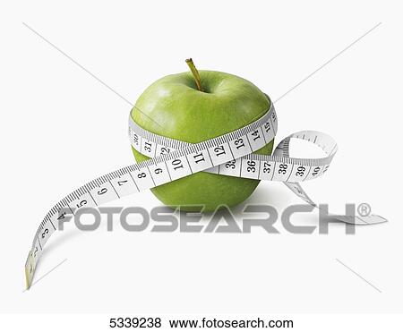 Stock Photo - A measuring tape wrapped around a green apple. Fotosearch