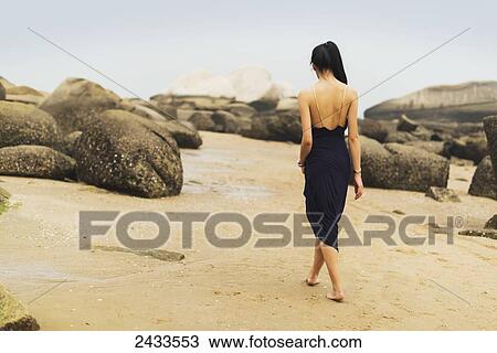 A model in formal dress walks barefoot on the sandy beach; Xiamen, China View Large Photo Image Stock Image - A model in formal dress walks barefoot on the sandy beach; Xiamen, China. Fotosearch