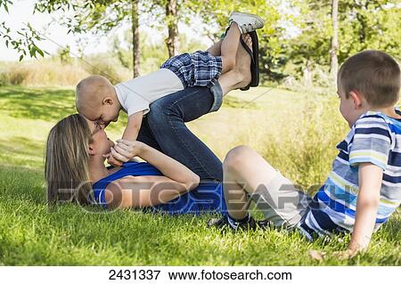 Stock Photo - A mother playing with her sons in a park; Edmonton, Alberta, Canada. Fotosearch