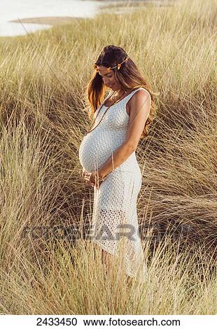 A pregnant woman stands in tall grasses at the coast; Tarifa, Cadiz, Andalusia, Spain View Large Photo Image Stock Image - A pregnant woman stands in tall grasses at the coast; Tarifa, Cadiz, Andalusia, Spain. Fotosearch