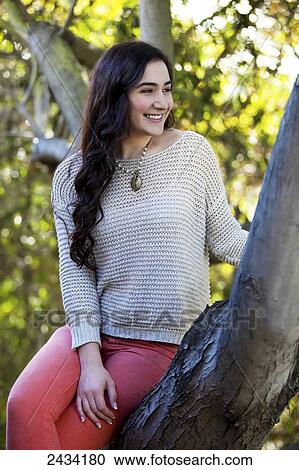 Stock Image - A teenaged girl sitting in a tree; San Francisco, California, United States of America. Fotosearch