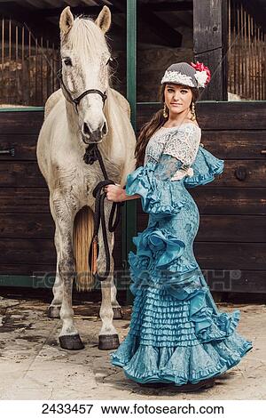 Stock Photo - A woman in formal flamenco dress standing with a horse; Tarifa, Cadiz, Andalusia, Spain. Fotosearch