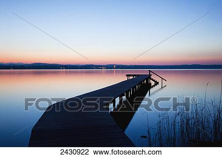 A wooden dock leading out to a tranquil lake at sunset; Starnberger See, Bavaria, Germany View Large Photo Image Stock Image - A wooden dock leading out to a tranquil lake at sunset; Starnberger See, Bavaria, Germany. Fotosearch