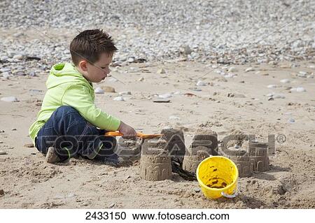 Stock Image - A young boy plays on the beach building a sand castle; South Shields, Tyne and Wear, England. Fotosearch