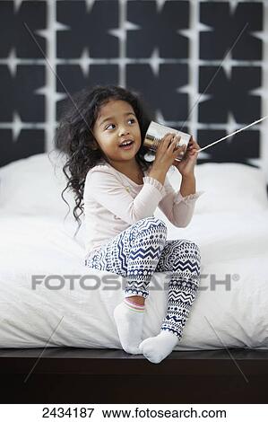 Stock Photo - A young girl is playing with a can and string communication device; San Francisco, California, United States of America. Fotosearch