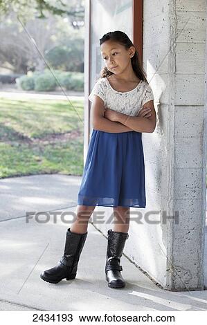 Stock Image - A young girl standing alone beside a building; San Francisco, California, United States of America. Fotosearch