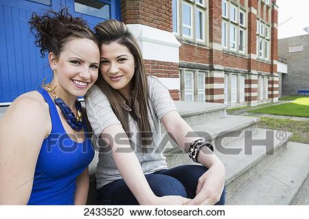 Stock Image - Best friends hanging out on school steps; Edmonton, Alberta, Canada. Fotosearch
