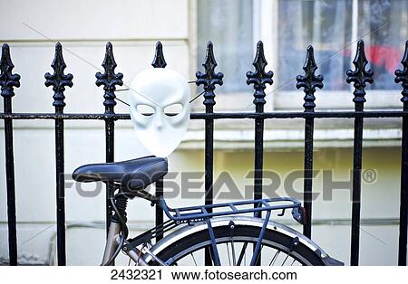 Stock Image - Bike leaning against a metal fence with a white mask, Notting Hill; London, England. Fotosearch