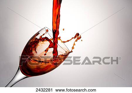 Stock Image - Close up of red wine being poured into a wine glass and splashing out; Calgary, Alberta, Canada. Fotosearch