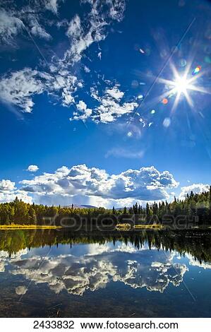 Stock Image - Clouds and boreal forest reflect on 48 Mile Pond, Chena River State Recreation Area; Fairbanks, Alaska, United States of America. Fotosearch