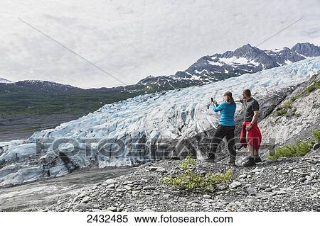 Couple taking a photograph with a cell phone in front of Shoup glacier, Shoup Bay State Marine Park, Prince William Sound; Valdez, Alaska, United States of America View Large Photo Image Stock Photography - Couple taking a photograph with a cell phone in front of Shoup glacier, Shoup Bay State Marine Park, Prince William Sound; Valdez, Alaska, United States of America. Fotosearch