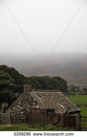 Dense fog over the hills with a small stone house in the foreground; Northumberland, England View Large Photo Image Stock Photo - Dense fog over the hills with a small stone house in the foreground; Northumberland, England. Fotosearch