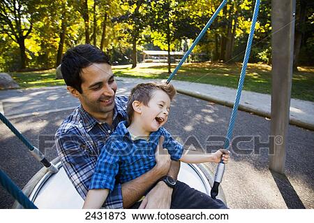 Father and son having fun together at a playground on a dish swing; Langley, British Columbia, Canada View Large Photo Image Stock Image - Father and son having fun together at a playground on a dish swing; Langley, British Columbia, Canada. Fotosearch