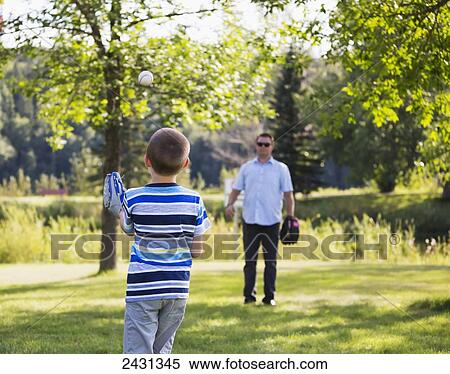 Stock Photography - Father and son playing baseball in a park; Edmonton, Alberta, Canada. Fotosearch
