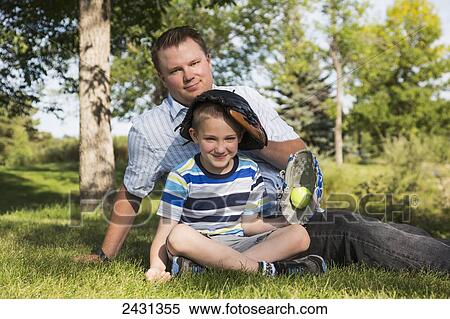 Father and son relaxing after playing baseball in a park; Edmonton, Alberta, Canada View Large Photo Image Stock Photography - Father and son relaxing after playing baseball in a park; Edmonton, Alberta, Canada. Fotosearch