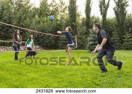 Stock Photo - Father playing volleyball in the backyard with his daughters; Sherwood Park, Alberta, Canada. Fotosearch