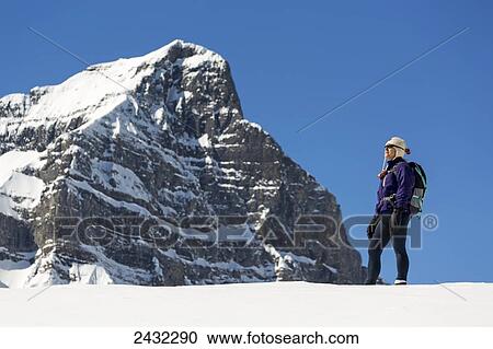 Female snowshoer on top of plateau looking out with snow covered mountain peak in the background and blue sky; Lake Louise, Alberta, Canada View Large Photo Image Stock Image - Female snowshoer on top of plateau looking out with snow covered mountain peak in the background and blue sky; Lake Louise, Alberta, Canada. Fotosearch