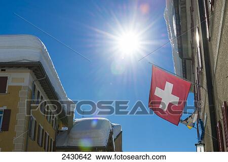 Flag of Switzerland hanging from a building with a sunburst in a blue sky; San Bernardino, Grisons, Switzerland View Large Photo Image Stock Image - Flag of Switzerland hanging from a building with a sunburst in a blue sky; San Bernardino, Grisons, Switzerland. Fotosearch