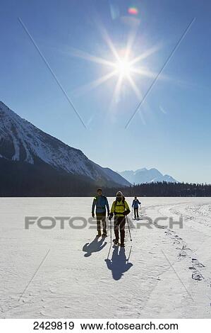 Group snowshoeing on snow covered mountain lake with sunburst and blue sky; Field, British Columbia, Canada View Large Photo Image Stock Photo - Group snowshoeing on snow covered mountain lake with sunburst and blue sky; Field, British Columbia, Canada. Fotosearch