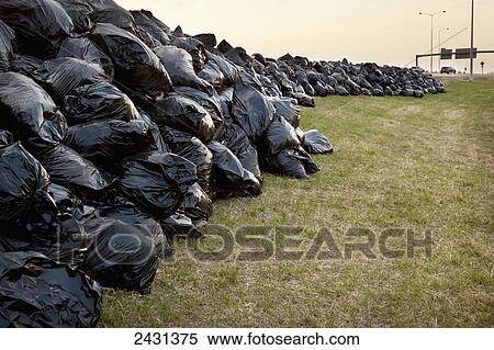 Stock Photography - Hundreds of full black garbage bags along the Anthony Henday Highway; Edmonton, Alberta, Canada. Fotosearch