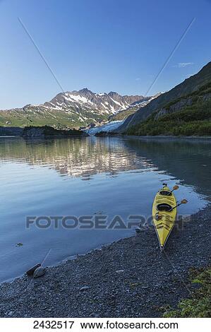 Stock Photo - Kayak on the beach with Shoup Glacier spilling over the Chugach mountains into Shoup Bay, Shoup Bay State Marine Park, Prince William Sound; Valdez, Alaska, United States of America. Fotosearch