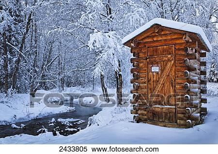Stock Photography - Log outhouse by a meandering creek in snow, Chena Hot Springs Resort; Fairbanks, Alaska, United States of America. Fotosearch