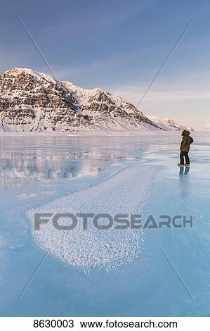 Man in a parka standing on overflow ice on the frozen Anaktuvuk River, Hoar frost crystals in the foreground, Napaktualuit Mountain in the background, Gates of the Arctic National Park; Alaska, United States of America View Large Photo Image Stock Image - Man in a parka standing on overflow ice on the frozen Anaktuvuk River, Hoar frost crystals in the foreground, Napaktualuit Mountain in the background, Gates of the Arctic National Park; Alaska, United States of America. Fotosearch