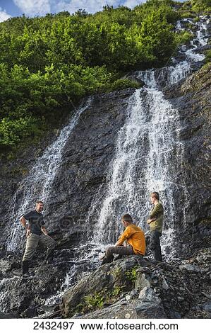Man with two teenage boys on the rocks in front of a waterfall at Shoup Bay State Marine Park, Prince William Sound; Valdez, Alaska, United States of America View Large Photo Image Stock Photo - Man with two teenage boys on the rocks in front of a waterfall at Shoup Bay State Marine Park, Prince William Sound; Valdez, Alaska, United States of America. Fotosearch