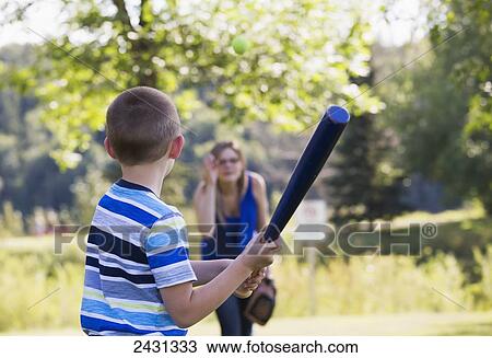 Stock Image - Mother and son playing baseball outdoors in a park; Edmonton, Alberta, Canada. Fotosearch