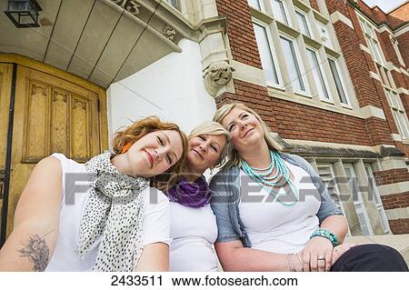 Stock Image - Mother and two daughters hanging out on school steps; Edmonton, Alberta, Canada. Fotosearch