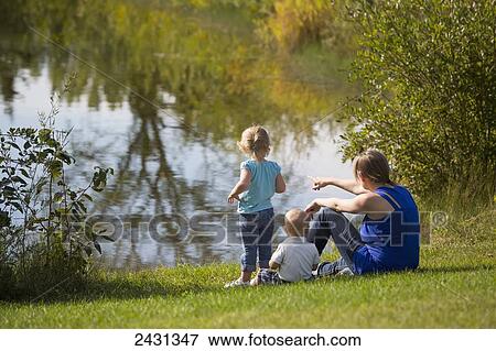 Mother and two young children sitting beside a lake in a park; Edmonton, Alberta, Canada View Large Photo Image Stock Photo - Mother and two young children sitting beside a lake in a park; Edmonton, Alberta, Canada. Fotosearch