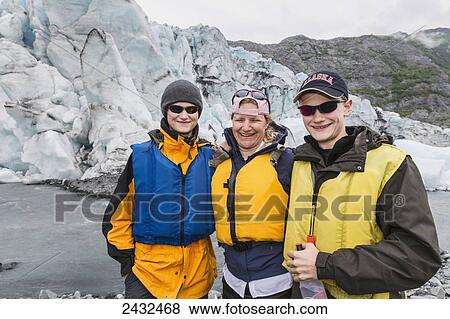 Stock Photo - Mother with two teenage sons wearing life jackets, standing in front of Shoup glacier and Chugach mountains, Shoup Bay State Marine Park, Prince William Sound; Valdez, Alaska, United States of America. Fotosearch
