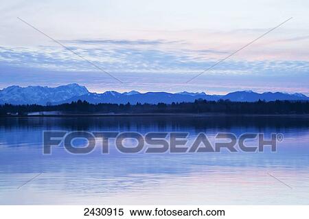 Mountain range and silhouette of a forest along the shoreline at sunset; Seeshaupt, Bavaria, Germany View Large Photo Image Stock Photography - Mountain range and silhouette of a forest along the shoreline at sunset; Seeshaupt, Bavaria, Germany. Fotosearch