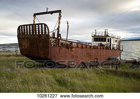 Stock Photo - Old fishing boat on the grass shore; Natales, Magallanes and Antartica Chilena Region, Chile. Fotosearch