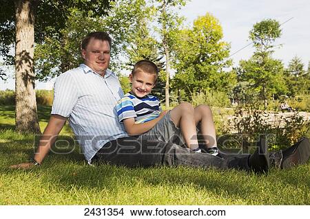 Portrait of a father and son hanging out in a park; Edmonton, Alberta, Canada View Large Photo Image Picture - Portrait of a father and son hanging out in a park; Edmonton, Alberta, Canada. Fotosearch