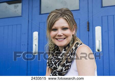 Stock Photography - Portrait of a young woman sitting in front of blue doors; Edmonton, Alberta, Canada. Fotosearch