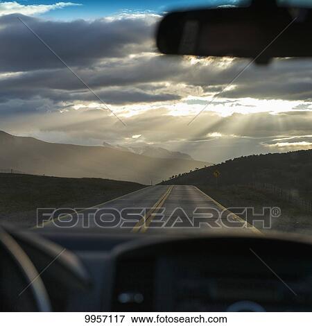 Rays of sunlight shining through the clouds onto the road as viewed through the windshield of a vehicle; Patagonia, Chile View Large Photo Image Stock Photo - Rays of sunlight shining through the clouds onto the road as viewed through the windshield of a vehicle; Patagonia, Chile. Fotosearch