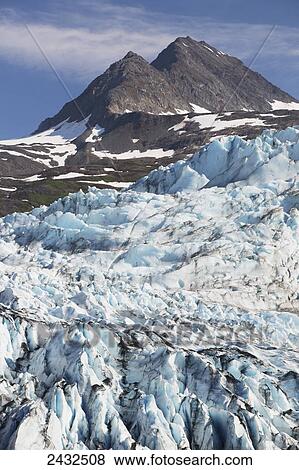 Stock Photo - Shoup Glacier spilling over the Chugach mountains, Shoup Bay State Marine Park, Prince William Sound; Valdez, Alaska, United States of America. Fotosearch