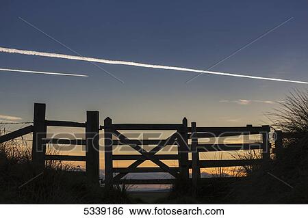 Silhouette of a fence at sunset with jet vapour in the sky; Northumberland, England View Large Photo Image Stock Photograph - Silhouette of a fence at sunset with jet vapour in the sky; Northumberland, England. Fotosearch
