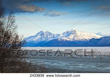 Stock Photo - Snow covered Chugach Mountains over Knik Arm with ice flows on the water in winter; Knik, Alaska, United States of America. Fotosearch