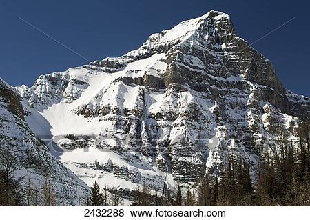 Stock Photo - Snow covered mountain peak with blue sky; Lake Louise, Alberta, Canada. Fotosearch