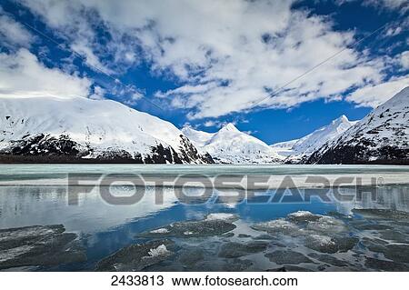 Snow covered mountain peaks reflected on the half frozen Portage Lake, Chugach National Forest; Alaska, United States of America View Large Photo Image Stock Image - Snow covered mountain peaks reflected on the half frozen Portage Lake, Chugach National Forest; Alaska, United States of America. Fotosearch